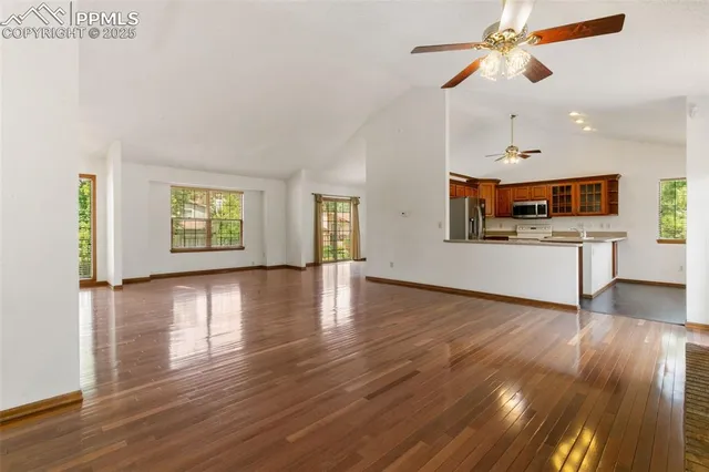 a view of a kitchen and an empty room with wooden floor