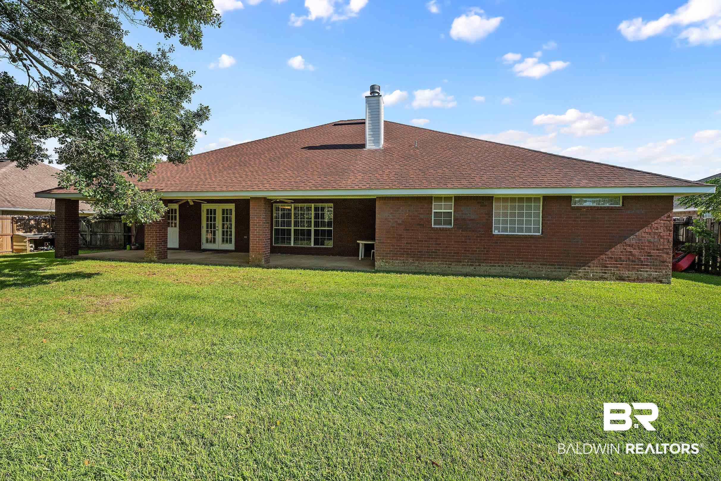 323 Manchester Lane Foley, AL 36535 - Photo 28 of 30 Expansive green lawn with a brick exterior, covered patio, French doors, and mature trees