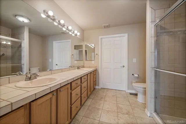 a bathroom with a double vanity sink toilet and shower