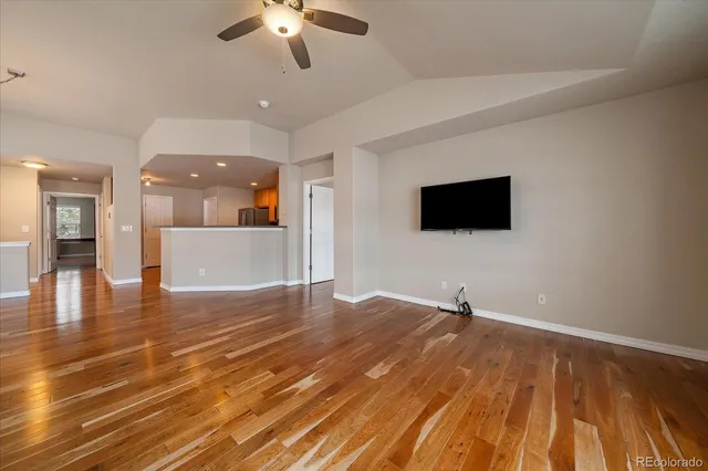 a view of a livingroom with a flat screen tv wooden floor and a ceiling fan