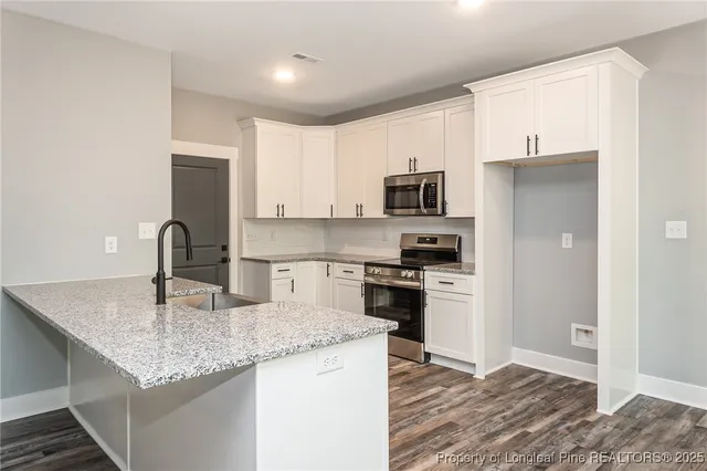 a kitchen with kitchen island granite countertop a stove top oven a sink and dishwasher