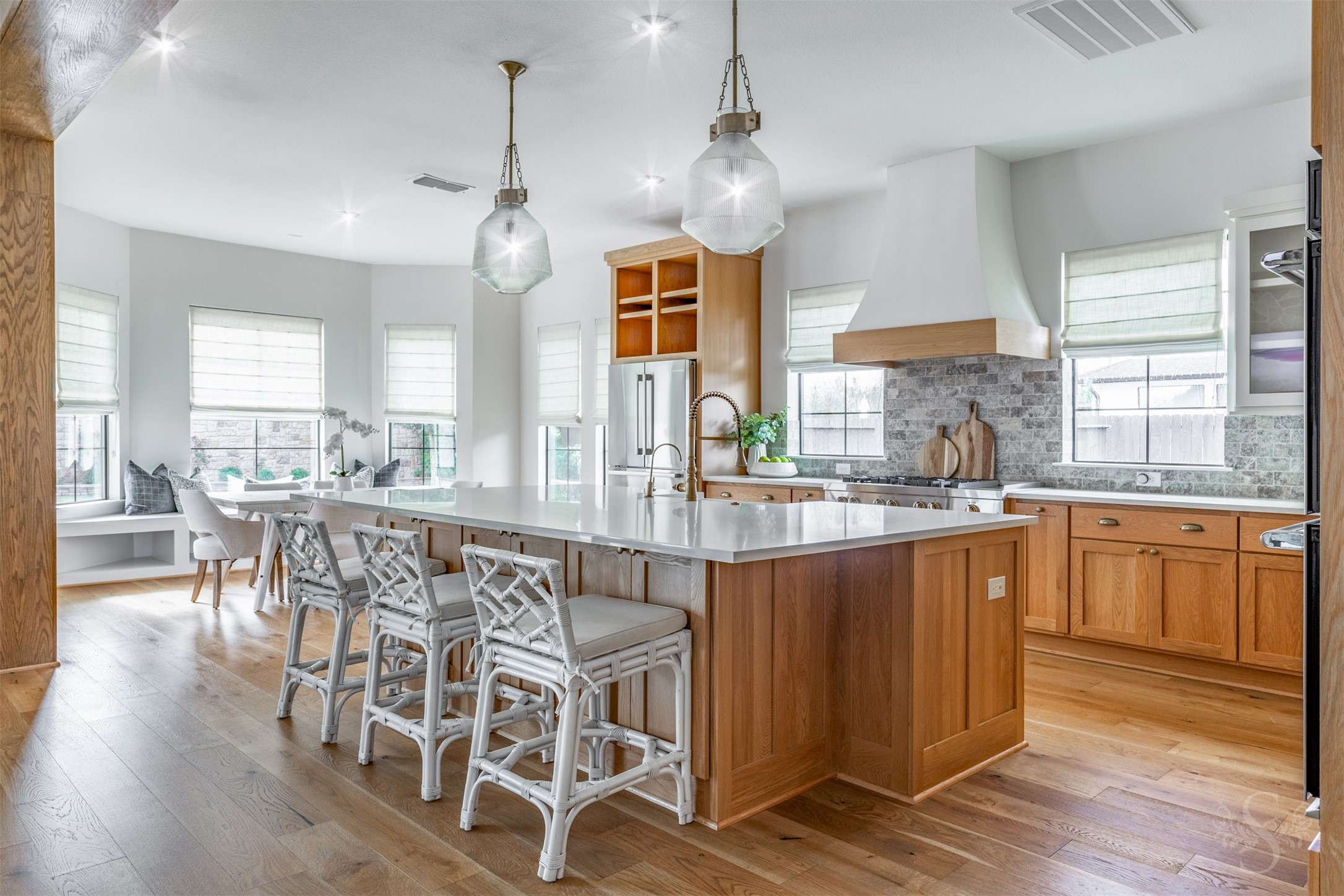 27919 Indigo Ridge Drive Fulshear, TX 77441 - Photo 18 of 50 This stunning chef-inspired kitchen showcases a huge Quartz island with seating, custom pendant lighting, and a gorgeous blend of warm wood cabinetry and crisp white glass-front uppers. High-end stainless steel appliances, double ovens, designer backsplash, and abundant natural light create a space that’s as functional as it is beautiful.