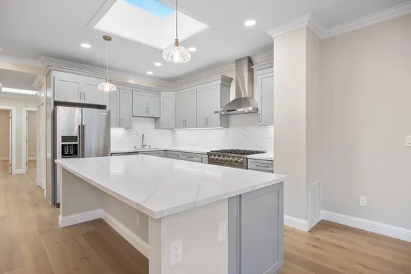 a kitchen with kitchen island a sink stainless steel appliances and wooden floor