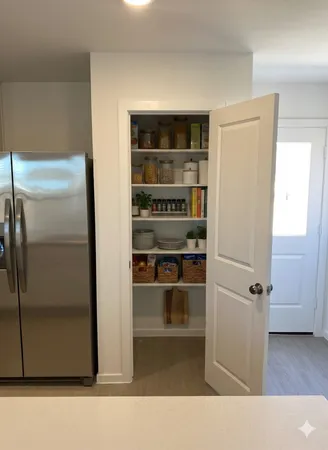 a view of a refrigerator in kitchen and an empty room