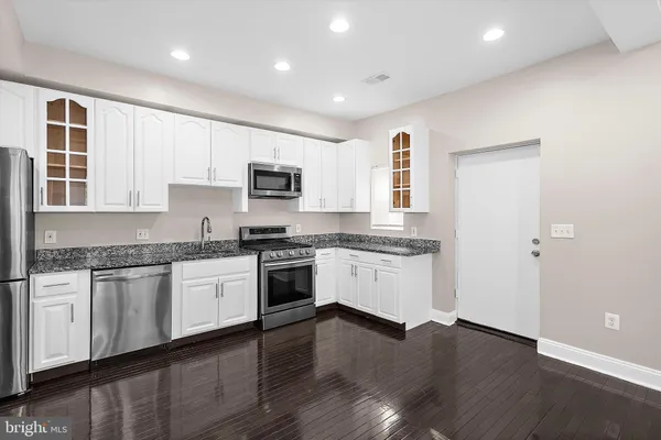 a kitchen with granite countertop white cabinets and black stainless steel appliances