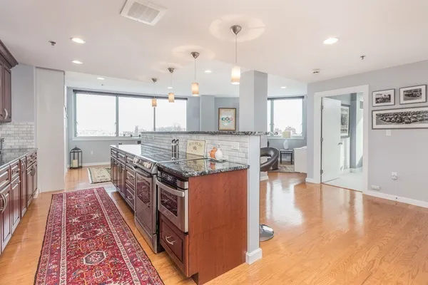 a large kitchen with stainless steel appliances granite countertop a stove and a wooden floors
