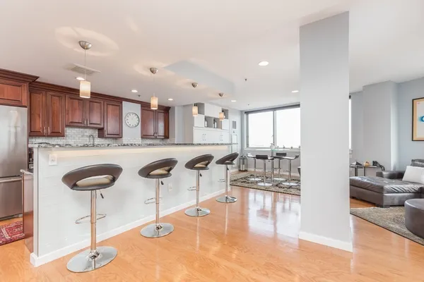 a kitchen with stainless steel appliances granite countertop a refrigerator a stove a sink and a dining table with wooden floor