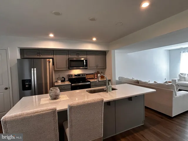 a kitchen with sink a refrigerator and chairs