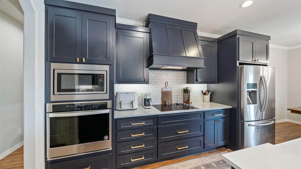 101 Lighthouse Lane Mabank, TX 75143 - Photo 15 of 40 Kitchen featuring stainless steel appliances, dark wood-type flooring, crown molding, tasteful backsplash, and light stone countertops