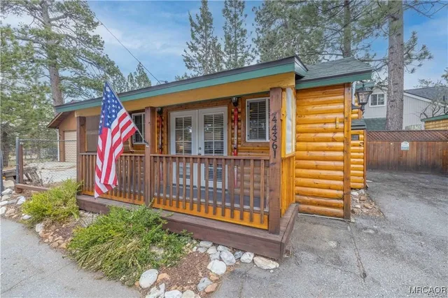 a view of a small deck with large trees and wooden fence