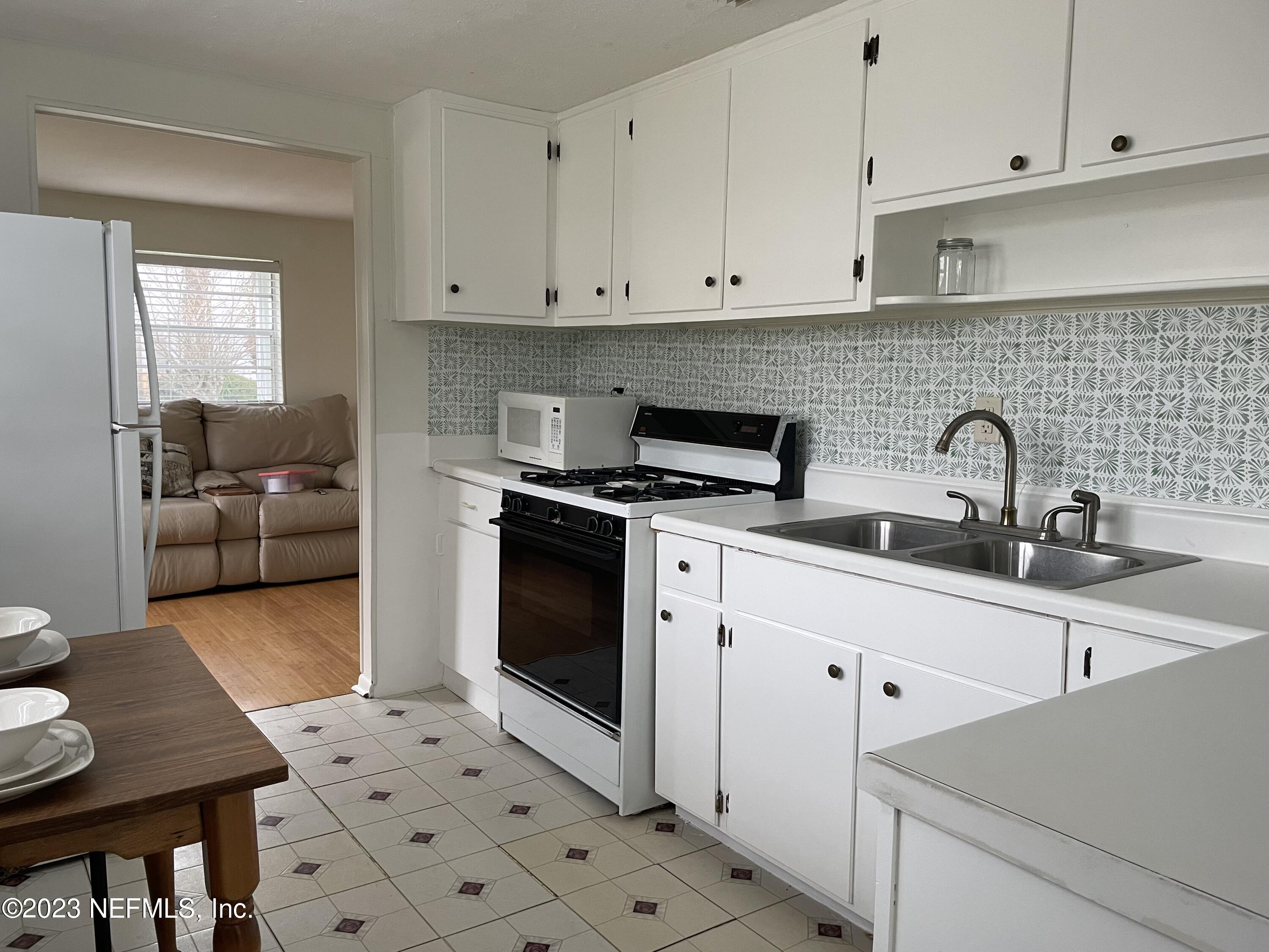 60 Jackson Road Atlantic Beach, FL 32233 - Photo 22 of 42 a kitchen with stainless steel appliances a stove a sink and white cabinets