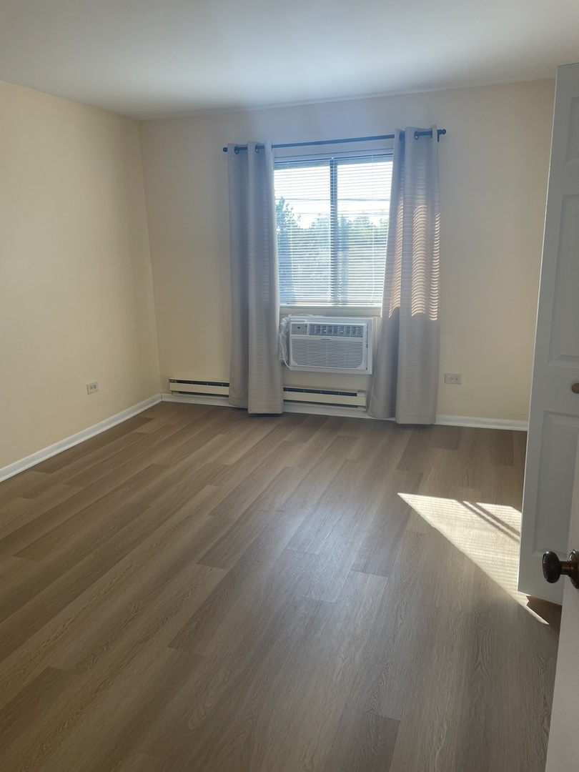 4150 Central Road, Unit 3E Glenview, IL 60025 - Photo 3 of 8 an empty room with wooden floor and windows