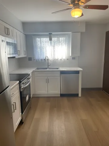 a kitchen with white cabinets a sink a stove and a window