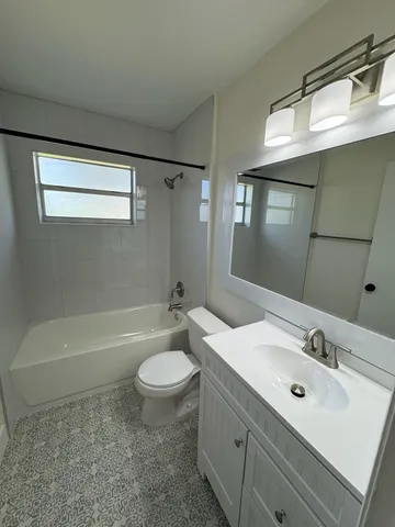 a bathroom with a sink a toilet a mirror and bathtub