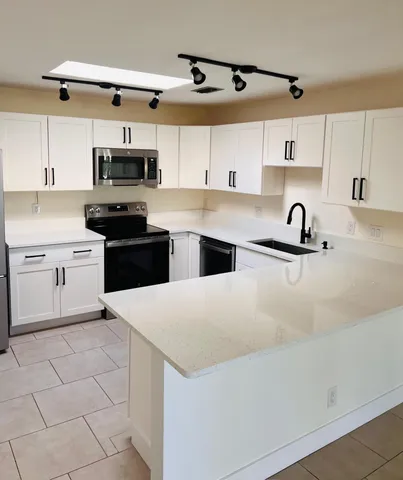 a kitchen with stainless steel appliances a sink a stove a microwave and cabinets