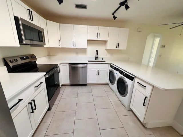 a kitchen with a sink a stove top oven and white cabinets