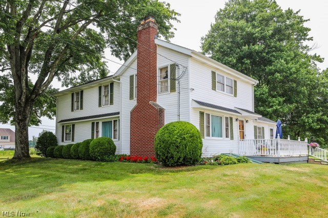 View of front facade featuring a wooden deck and a front lawn