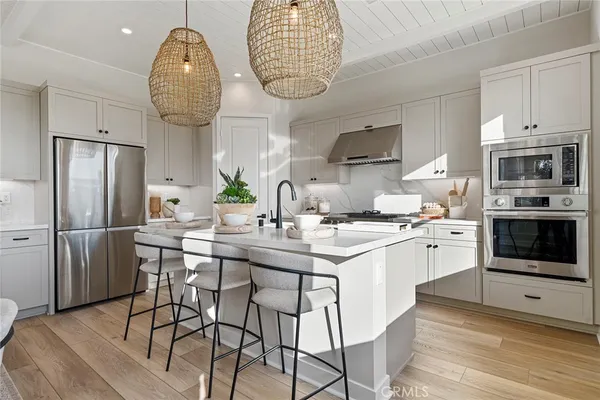 a kitchen with stainless steel appliances a dining table a stove a microwave a refrigerator and cabinets