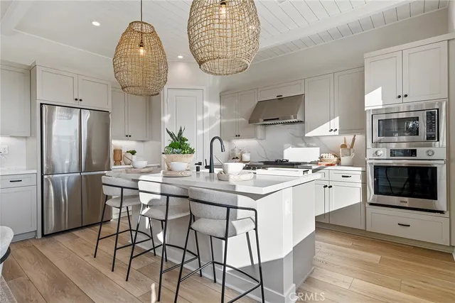 a kitchen with stainless steel appliances a dining table a stove a microwave a refrigerator and cabinets