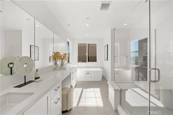 a large white bathroom with a double vanity sink a mirror and a bathtub