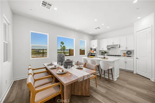 a open dining room with stainless steel appliances kitchen island granite countertop a dining table chairs and a refrigerator