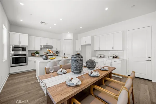 a kitchen with a dining table and chairs with wooden floor