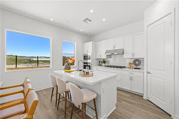 a kitchen with a dining table chairs and white cabinets