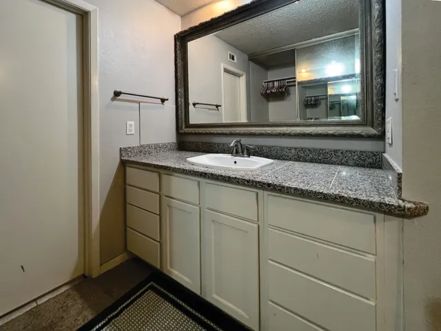 a bathroom with a granite countertop sink and a mirror