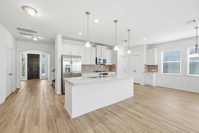 a view of kitchen with kitchen island wooden floor center island and stainless steel appliances