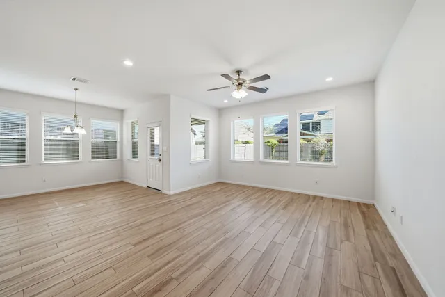 a view of an empty room with a window and wooden floor
