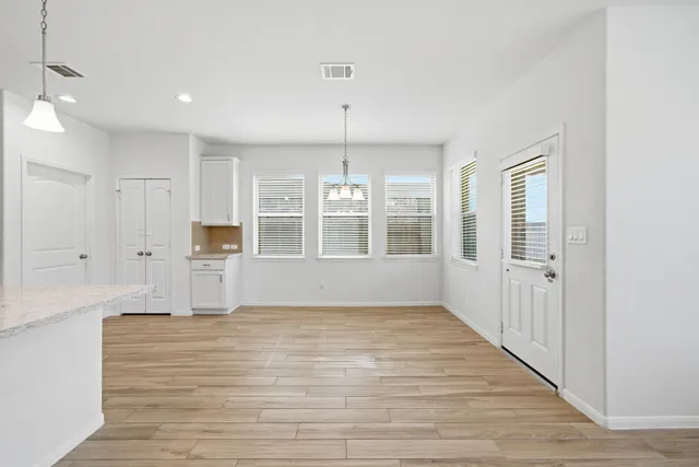 a view of empty room with wooden floor and windows