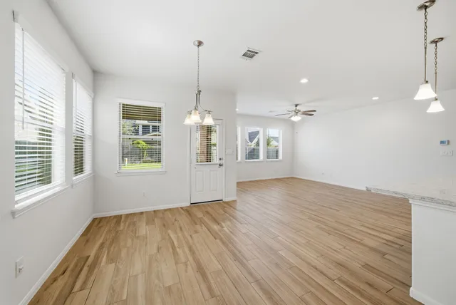 a view of empty room with wooden floor and windows