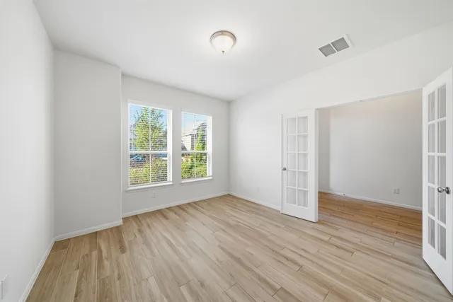 a view of an empty room with wooden floor and a window