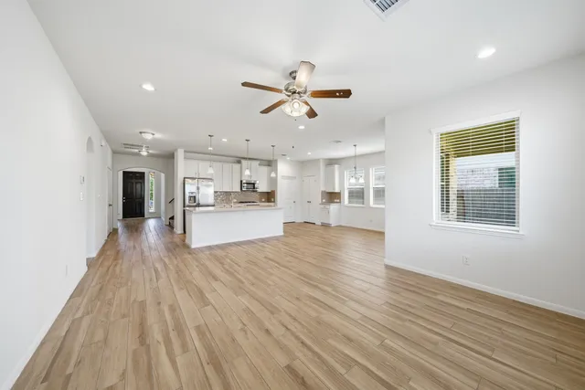 a view of a big room with wooden floor and a kitchen