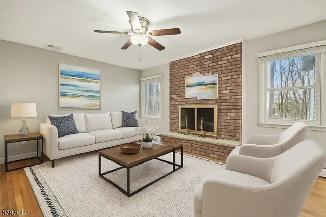 a view of an empty room with wooden floor fireplace and a window