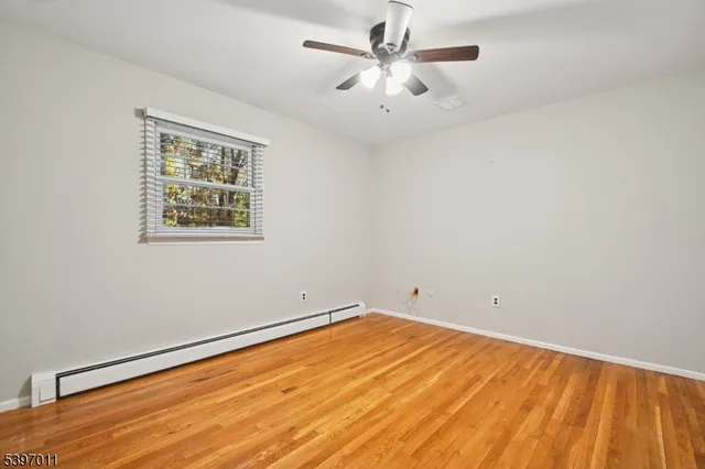 a view of a room with wooden floor and a ceiling fan