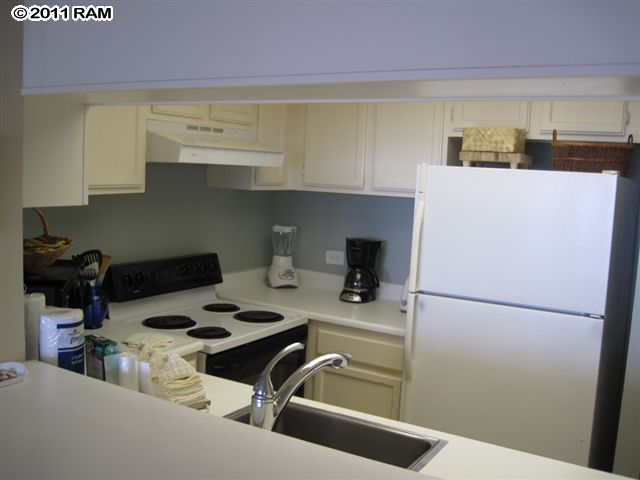 4401 Lower Honoapiilani Road, Unit A604 Lahaina, HI 96761 - Photo 9 of 29 a kitchen with a refrigerator and a stove top oven