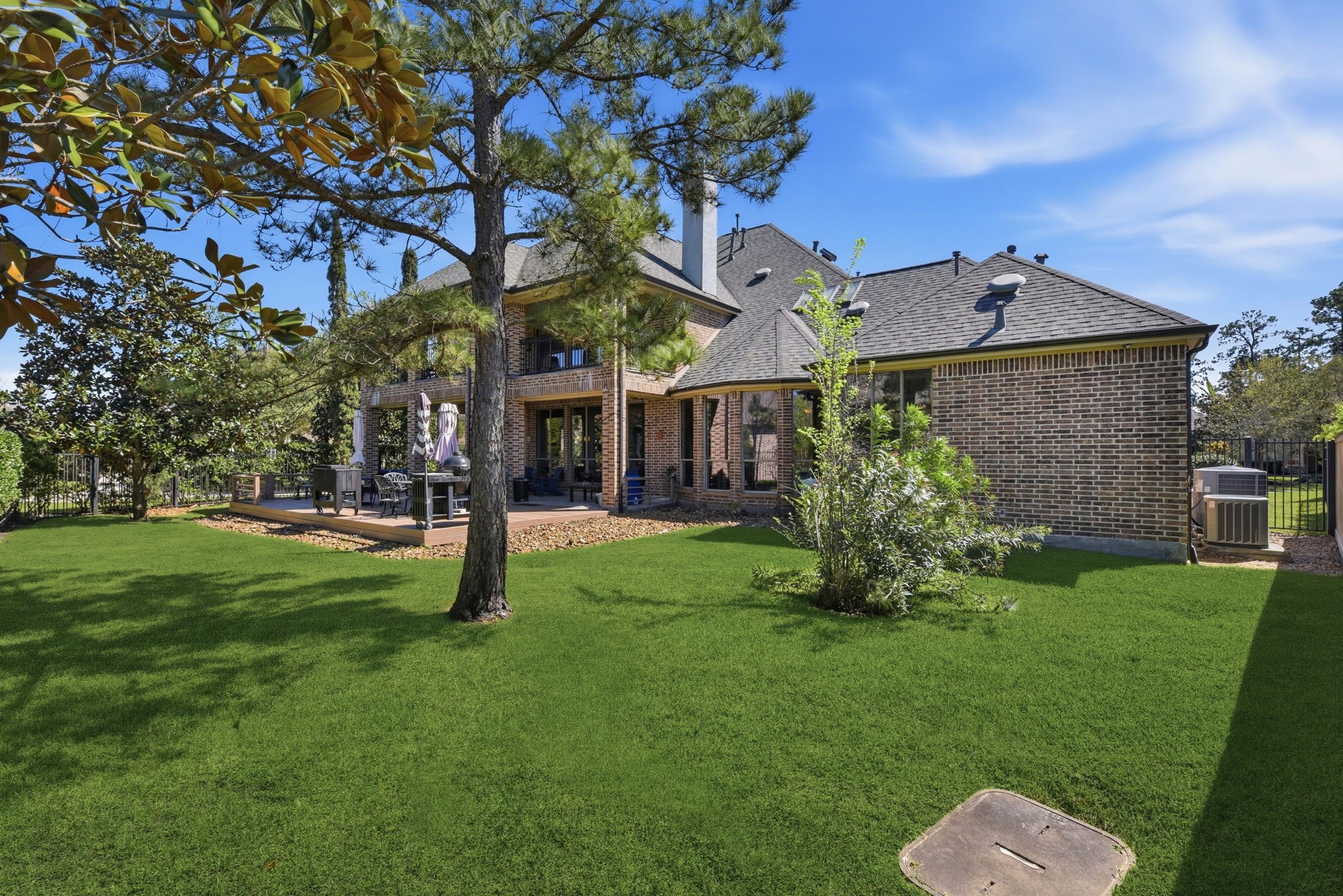 223 South Bauer Point Circle Spring, TX 77389 - Photo 37 of 50 This beautiful brick home features a spacious backyard with lush green grass and mature trees, offering a serene outdoor space. The patio area provides a perfect spot for relaxation or entertaining.