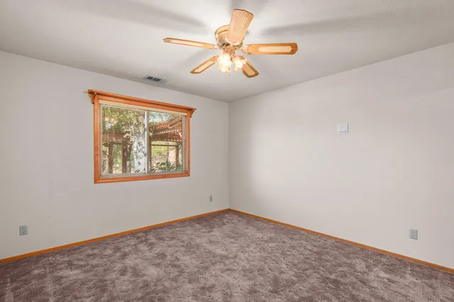 an empty room with windows and fan