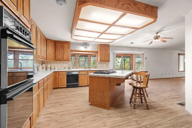 a kitchen with stainless steel appliances granite countertop a stove a sink dishwasher a microwave oven with a dining table and chair with wooden floor
