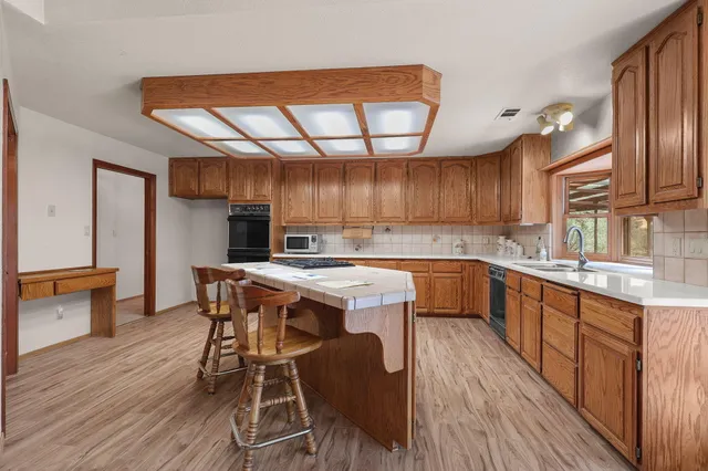 a kitchen with a table chairs a sink dishwasher stove and wooden cabinets