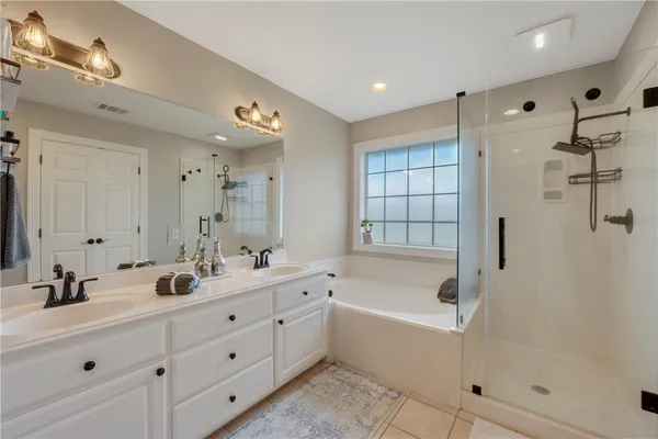 a bathroom with a tub sink double vanity and mirror