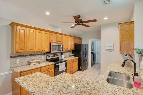 a kitchen with stainless steel appliances granite countertop a stove top oven a sink dishwasher a dining table and chairs with wooden floor