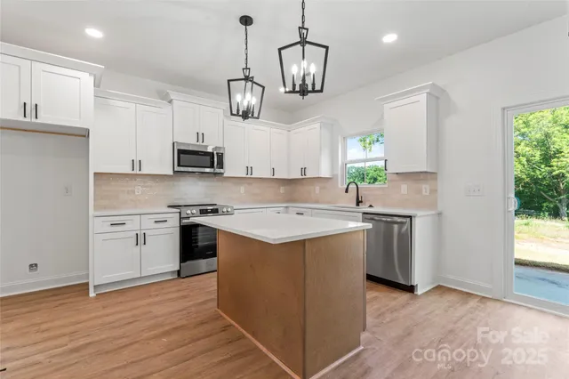 a view of a kitchen with a stove cabinets a ceiling fan and wooden floor