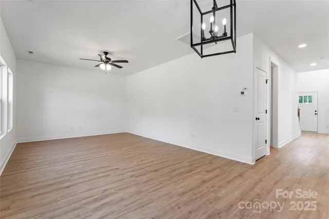 a view of an empty room and chandelier fan