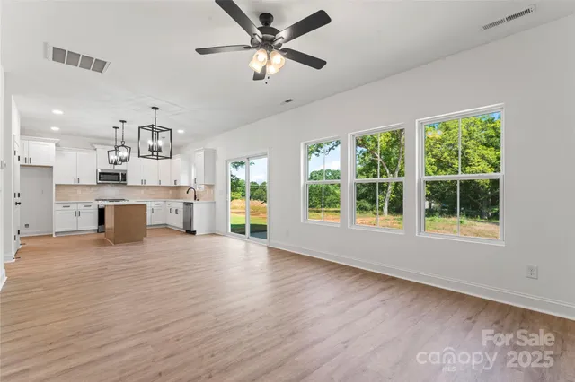 an empty room with windows and fan