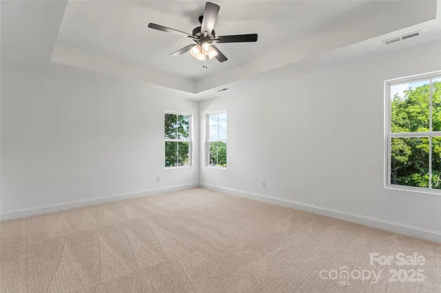 en empty room with windows and chandelier fan