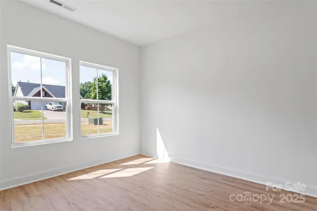 an empty room with wooden floor cabinet and windows