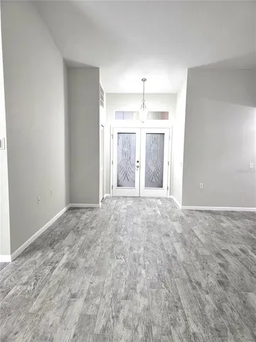 en empty room with a chandelier fan and kitchen view
