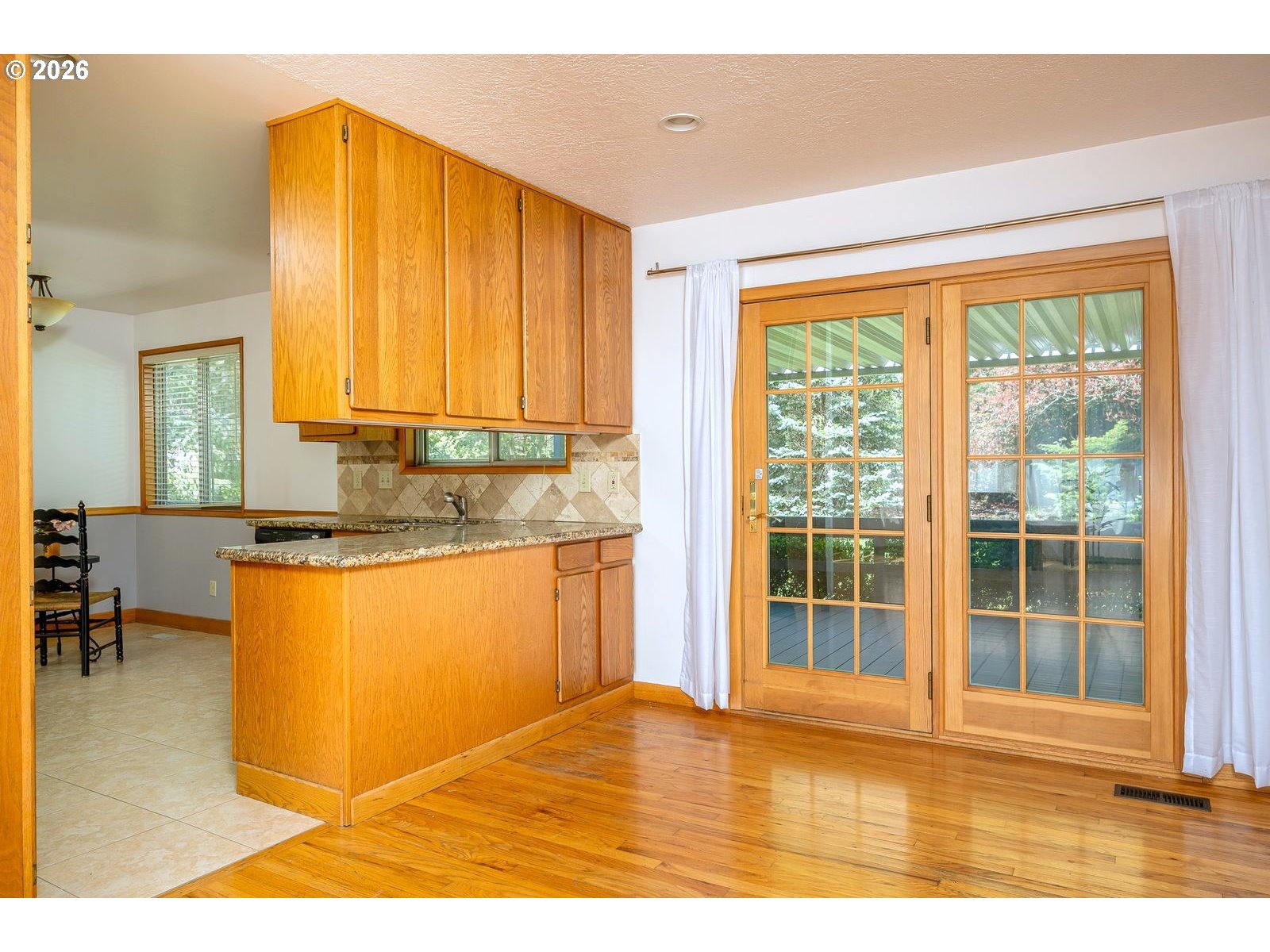 5815 Southwest Huddleson Street Portland, OR 97219 - Photo 6 of 35 a view of a kitchen with kitchen island a sink wooden floor and a large window